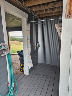 A covered outdoor area with a metal gate, a hose, and a small water pump. - Relaxing 5-bedroom house with one of the best views at Lake Mac. (Brule)
