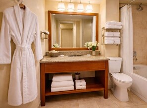 Ein Badezimmer mit hölzernem Waschtisch, einem Spiegel, einer Toilette und einer Badewanne.