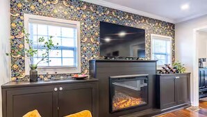 Una sala de estar con chimenea, televisor y pared con diseño.