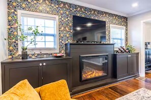 Ein Wohnzimmer mit Kamin, Fernseher und Wand mit Muster.