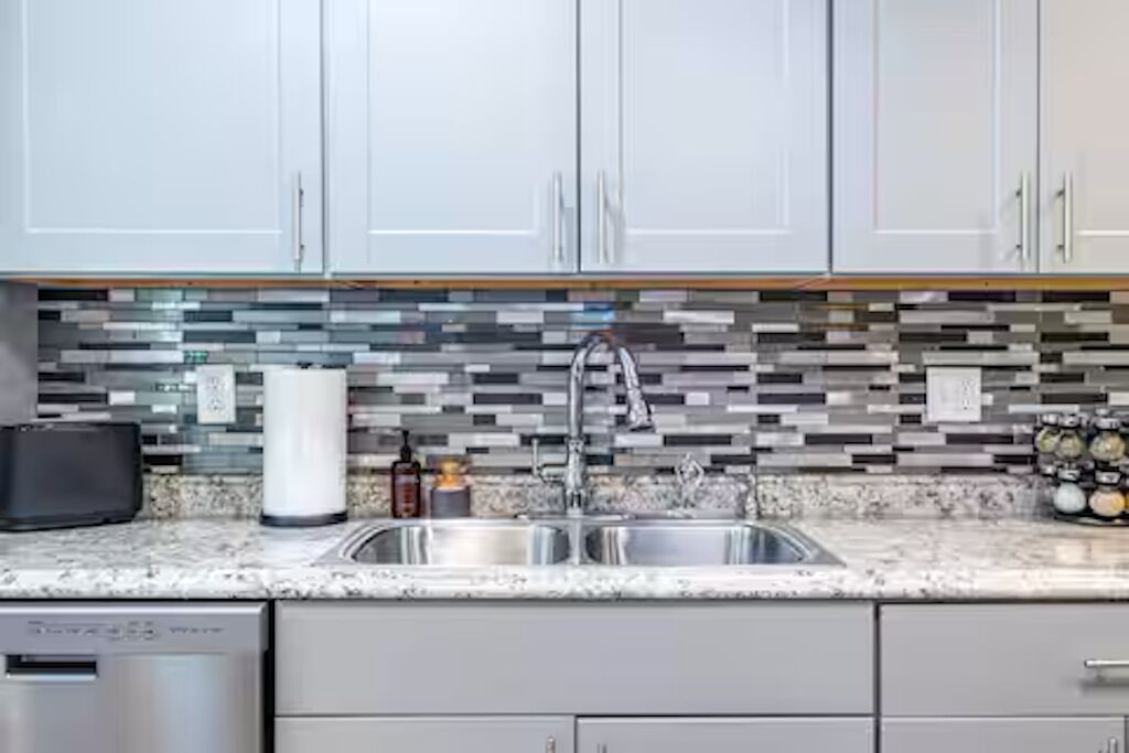 Una cucina dal design moderno, con lavello in acciaio inossidabile, macchina del caffè e lavastoviglie.