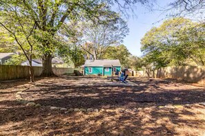 A backyard with a small house, a tree, and a blue chair. - Fuzzy Peach Bungalow: Huge Yard w/fire pit. Pet Friendly! (Atlanta)