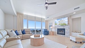 Un salón amplio con un ventanal grande, chimenea y ventilador de techo.