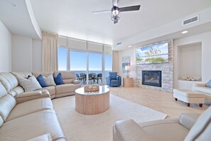 Ein geräumiges Wohnzimmer mit großem Fenster, Kamin und Deckenventilator.