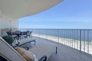 Ein Balkon mit Blick auf den Strand, Gartenmöbel und ein Grill.