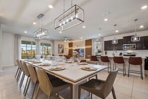A modern kitchen with dark cabinets, a large island, and pendant lighting. - Disney Dream Home | Mario, Frozen & Minions (Davenport)