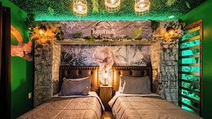 Quarto com cama, parede temática de 'Jurassic Park' e iluminação verde ambiente.