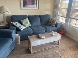 Ein Wohnzimmer mit einem blauen Sofa, einem Holztisch und einer Lampe.