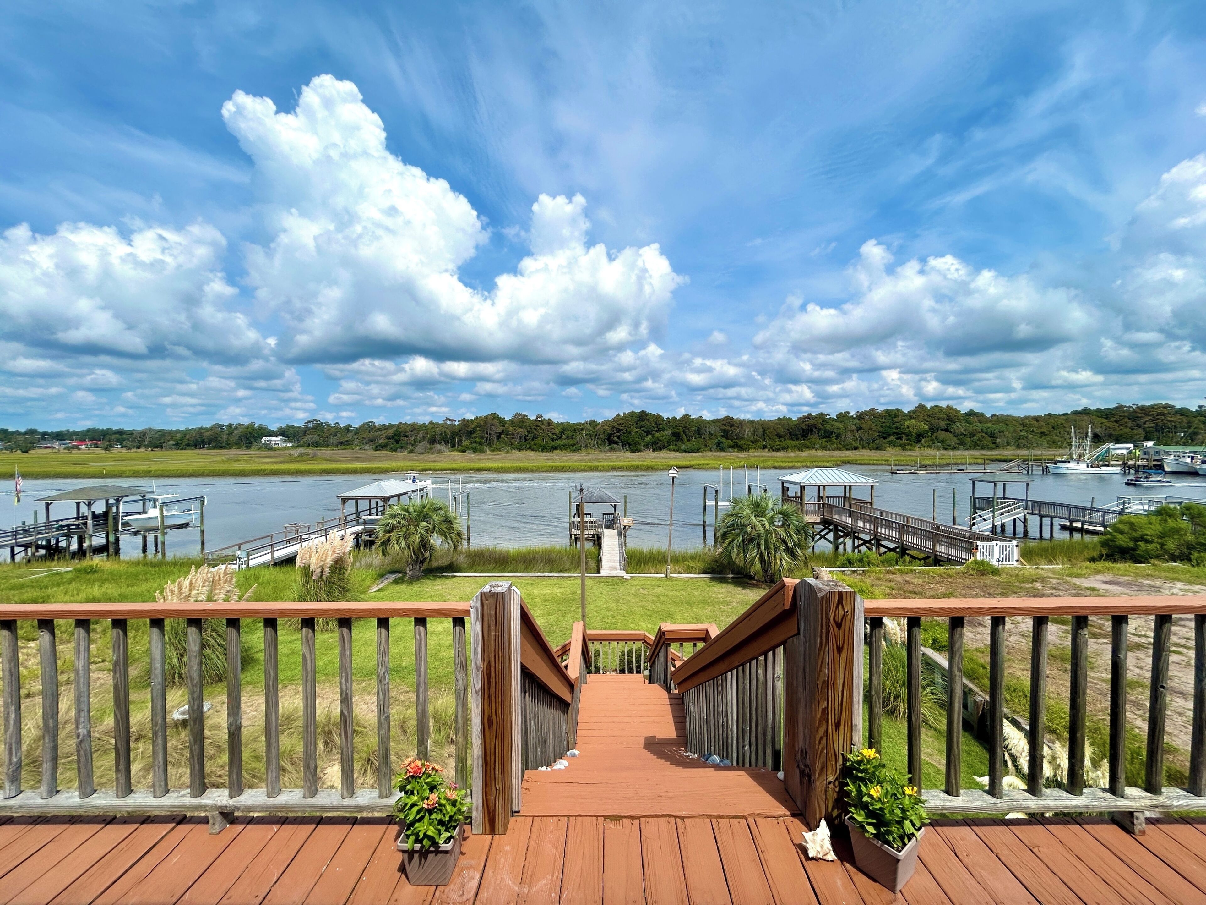 A wooden deck leading to a waterfront area with docks and boats.