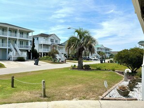 Hotel ved stranden med flere balkoner, en palme og en klar himmel.