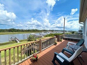 A wooden deck with a view of a marina and river. - Waterfront 4 bedroom retreat with dock and porch swing! (Holden Beach)
