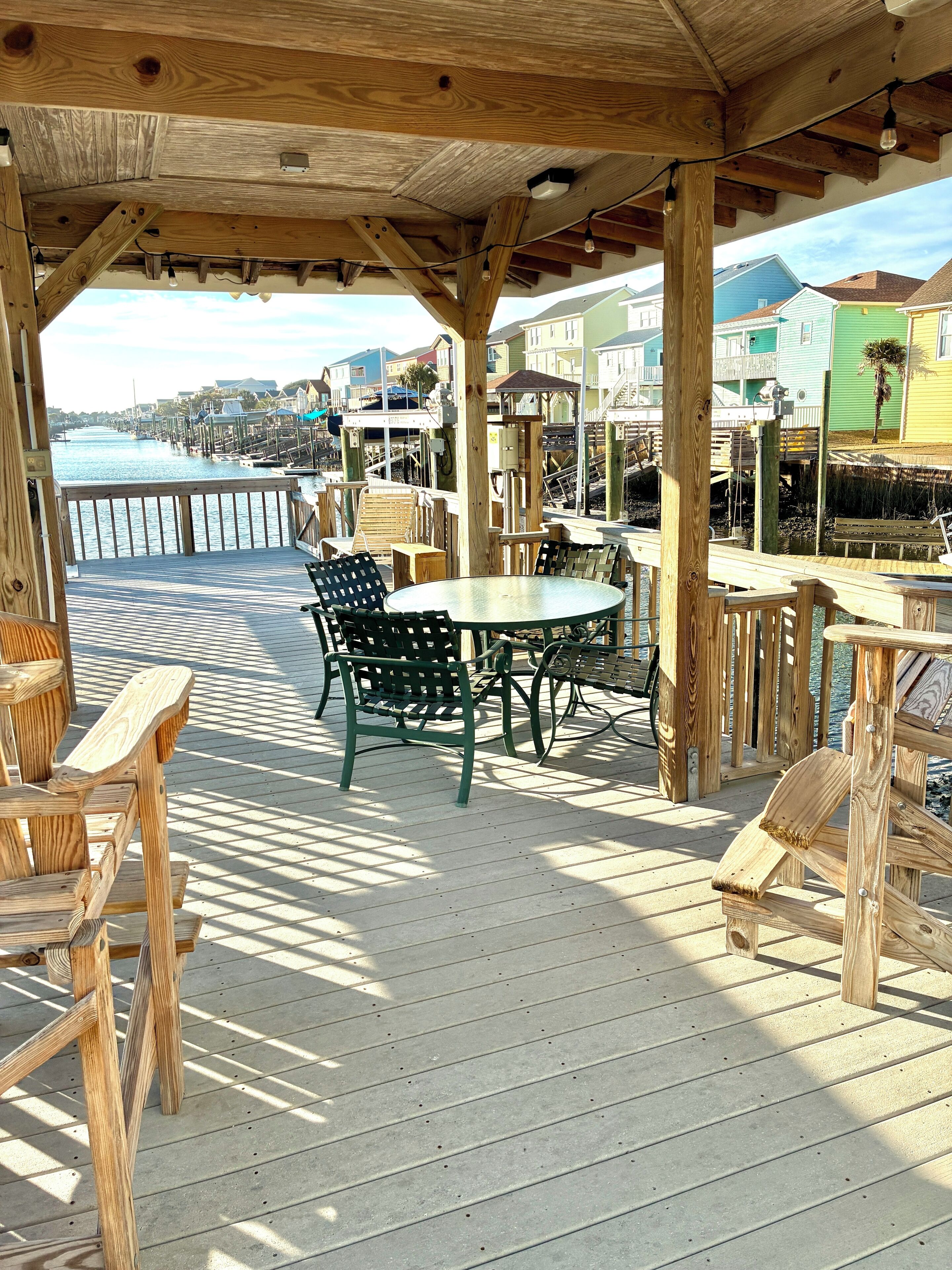 A wooden deck with outdoor seating, overlooking a waterfront area.
