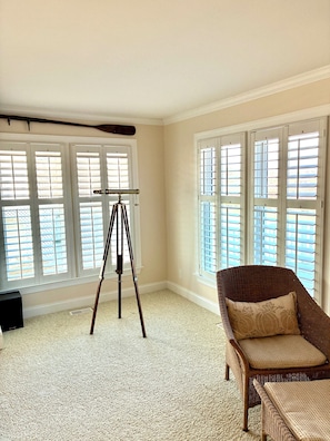 A room with a tripod stand, a wicker chair, and large windows with blinds. - Spacious 3-bedroom, 2-bath canal home located with Canal access and Waterway views. (Supply)