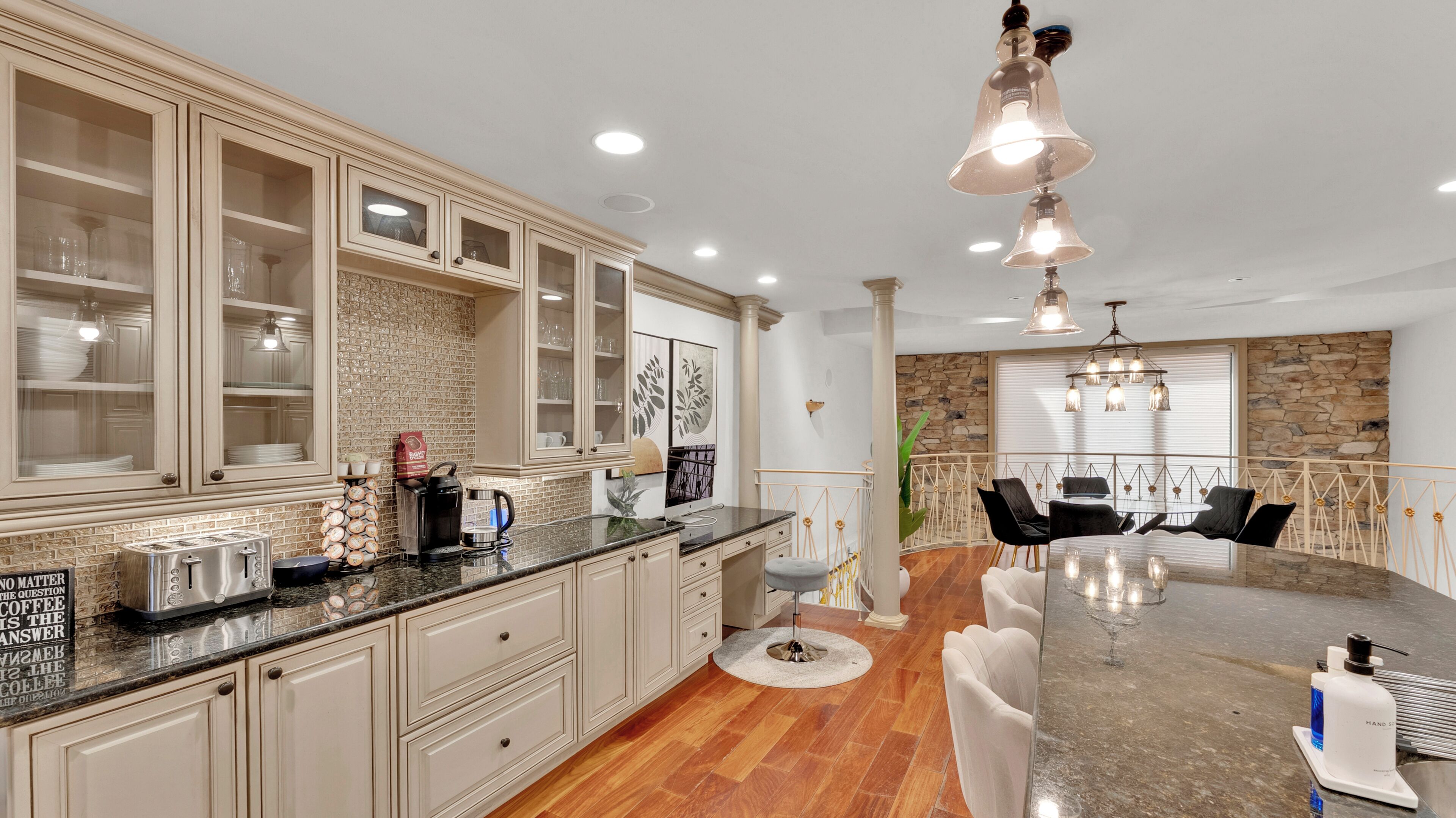 A spacious kitchen with a large island, a dining area with a stone accent wall, and a stone fireplace.