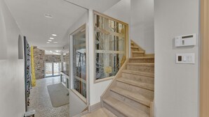 A modern interior with a staircase, a glass door with decorative elements, and a stone wall. - Apartment at S Front St Philadelphia (Philadelphia)
