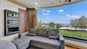 A modern living room with a large window, a sectional sofa, and a built-in entertainment unit. - Apartment at S Front St Philadelphia (Philadelphia)