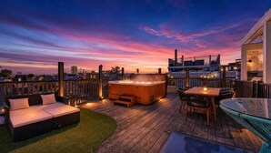A rooftop deck with a hot tub, seating area, and a glass table. - Apartment at S Front St Philadelphia (Philadelphia)
