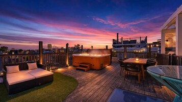 Terraza en la azotea con jacuzzi, zona de estar y una mesa de vidrio.