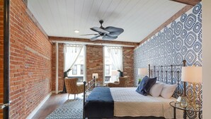 Een slaapkamer met een bed, een stoel, een tafel en een behang met patroon.