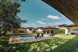 A modern house with a swimming pool, two lounge chairs, and a covered patio area. - 4 bedrooms Hacienda style home in Las Golondrinas, Hacienda Pinilla near beach (Tamarindo)