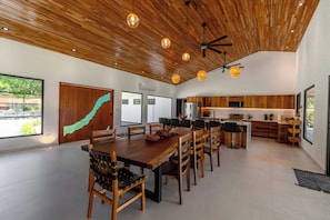 A spacious dining area with a wooden table and chairs, a kitchen with wooden cabinets, and a ceiling fan. - 4 bedrooms Hacienda style home in Las Golondrinas, Hacienda Pinilla near beach (Tamarindo)
