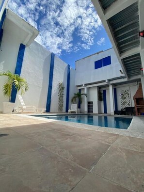 Un edificio moderno con piscina, detalles en azul y cielo despejado.