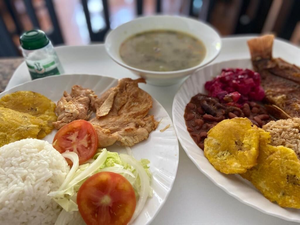 A plate with rice, a slice of tomato, lettuce, and a piece of meat.