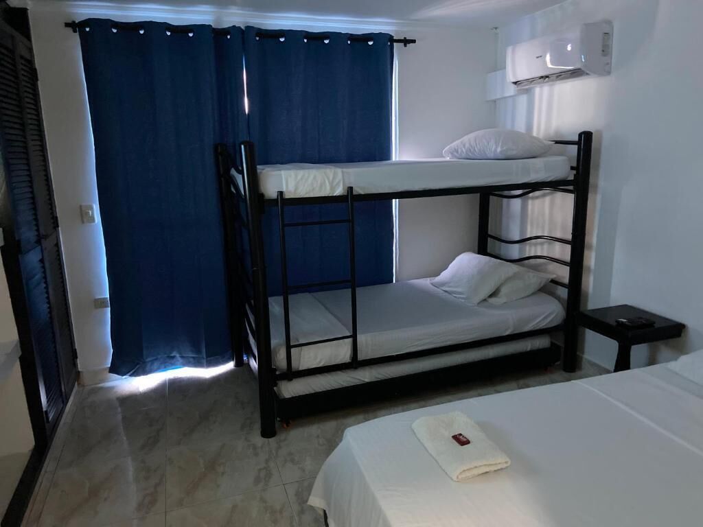 A bunk bed room with a window, a bedside table, and a bed with a white sheet.