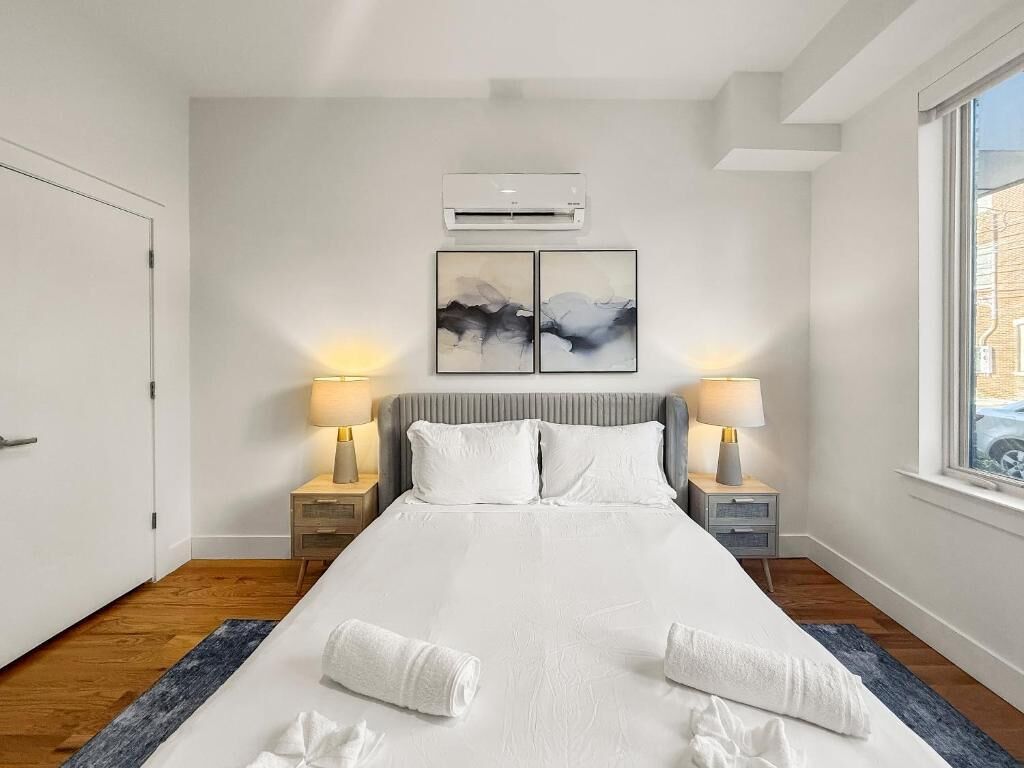 Ein Hotelzimmer mit einem großen Bett, zwei Nachttischlampen, einer Klimaanlage und zwei abstrakten Bildern an der Wand.