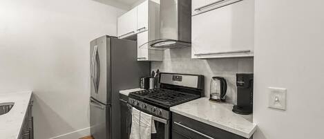 Una cocina compacta con refrigerador, estufa, horno y microondas.
