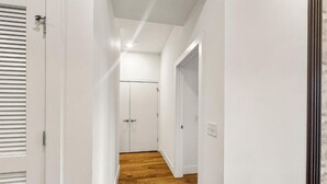 Passadís amb parets blanques, terres de fusta i una porta al final.