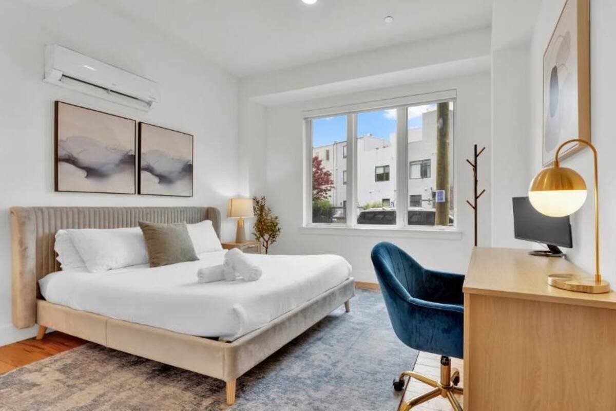 Une chambre moderne avec un lit, un bureau, une chaise et une grande fenêtre.