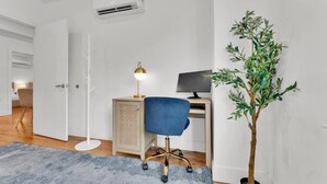 Una habitació amb escriptori, cadira, làmpada i una planta en test.