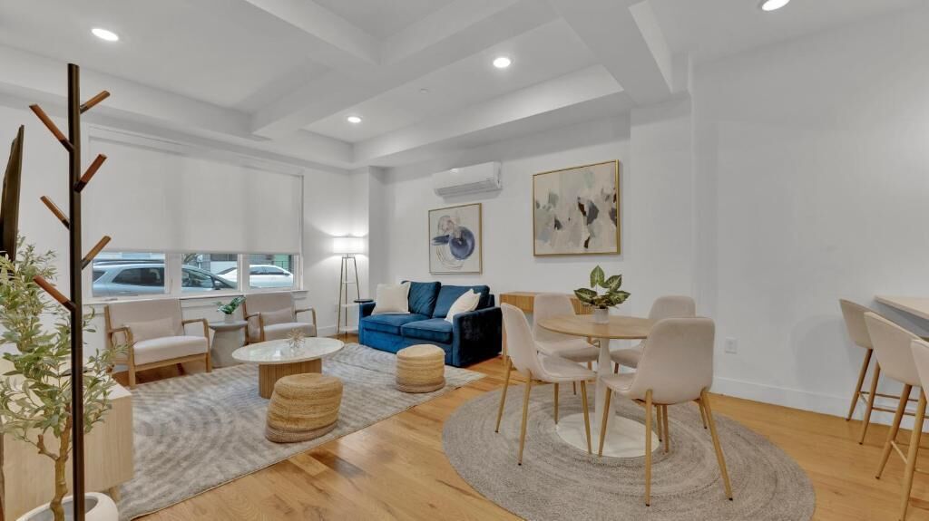 A modern living room with a blue sofa, white chairs, a round table, and a coffee table.