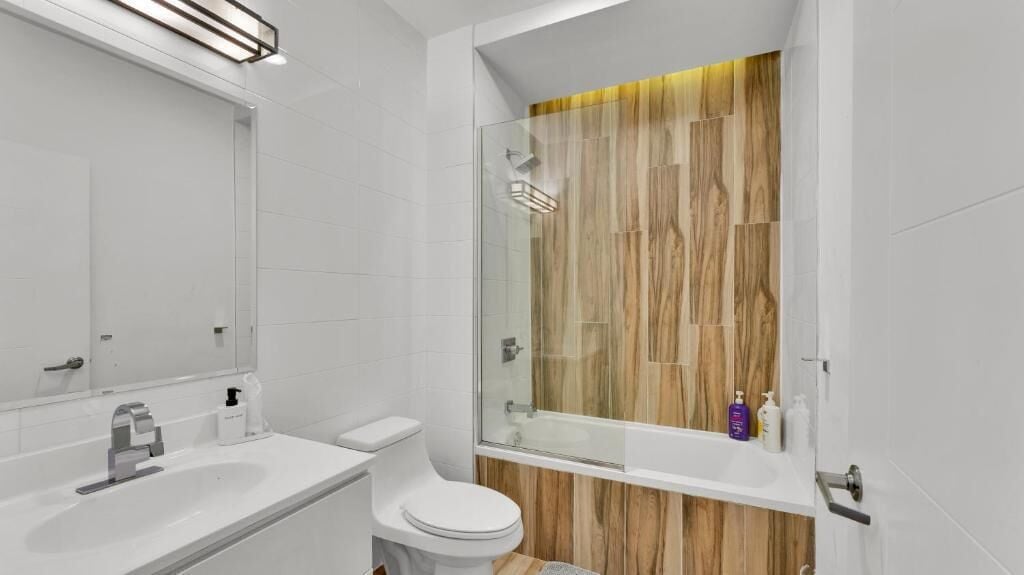A modern bathroom with a glass-enclosed shower, a white sink, and a toilet.