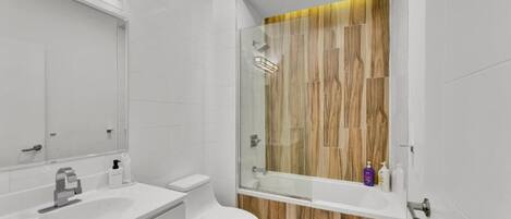 A modern bathroom with a glass-enclosed shower, a white sink, and a toilet.