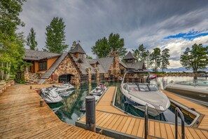Ein Yachthafen mit vertäuten Booten, einer Holzterrasse und Steinbauten mit steilen Dächern.