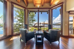 Ein Zimmer mit großen Fenstern, Korbmöbeln und Holzboden.
