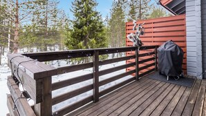 Eine Holzterrasse mit Geländer, einem Grill und einem überdachten Grillbereich.