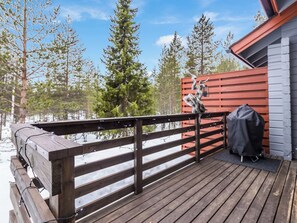 A wooden deck with a railing, a barbecue grill, and a covered grill area. - Luonnonrauha a by Interhome (Sodankylä)