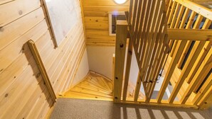 Eine Holztreppe mit Handlauf, einem Teppichboden und einer runden Leuchte an der Decke.