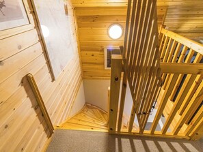 A wooden staircase with a handrail, a carpeted floor, and a circular light fixture on the ceiling. - Luonnonrauha a by Interhome (Sodankylä)