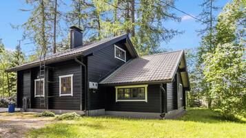 Een houten chalet met een schuin dak, schoorsteen en klein terras.