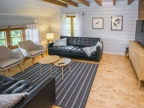 A modern living room with a black leather sofa, two armchairs, a coffee table, and a patterned rug. - Rustholli17 by Interhome (Salo)