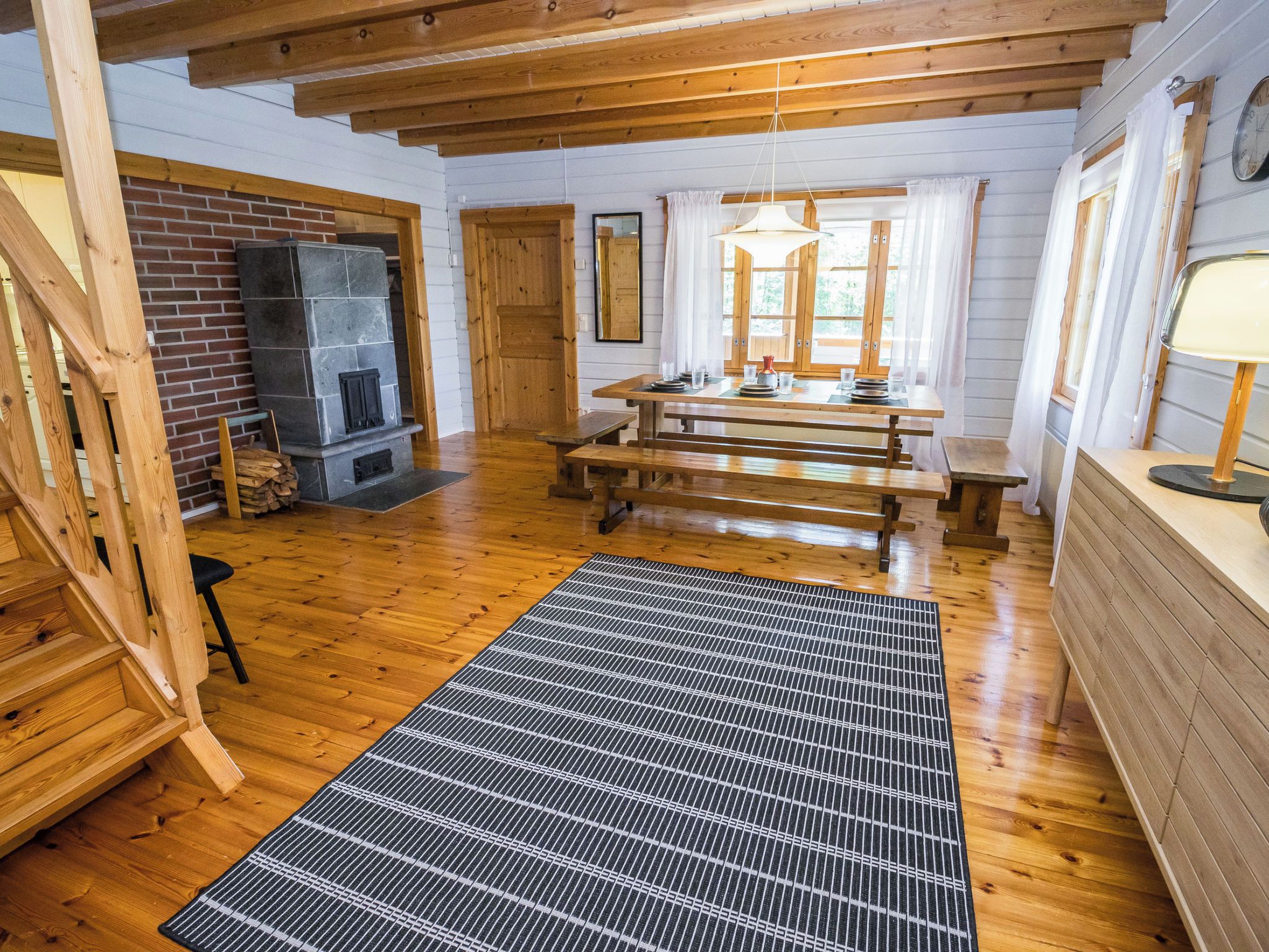 A wooden interior with a fireplace, a dining table, and benches.
