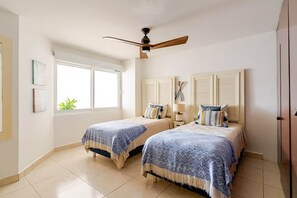 A bedroom with two beds, a ceiling fan, a window, and a door. - Luxury apartment Nuevo Vallarta Villa Magna condo (Nuevo Vallarta)