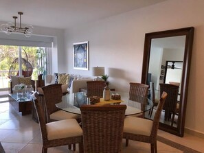 A dining area with wicker chairs, a glass table, and a large mirror on the wall. - Luxury apartment Nuevo Vallarta Villa Magna condo (Nuevo Vallarta)