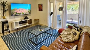 Un soggiorno con televisore, divano, tavolino e ventilatore a soffitto.