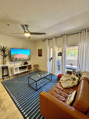 A living room with a TV, sofa, coffee table, and a ceiling fan. - Papago Park Oasis Near Sky Harbor Intl. (Phoenix)