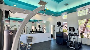 Una palestra con attrezzi da allenamento, una ventola a soffitto e ampie finestre.